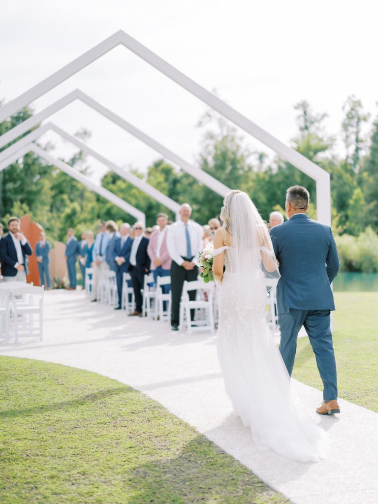 Dad walks his beautiful daughter down the aisle at our South Carolina wedding venue. She looks stunning walking under the open air chapel wedding ceremony site.