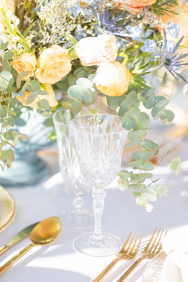 Spring 2026 wedding inspiration with a bride in a chic gown next to a romantic pastel tablescape with elegant stemware and pastel flowers.
