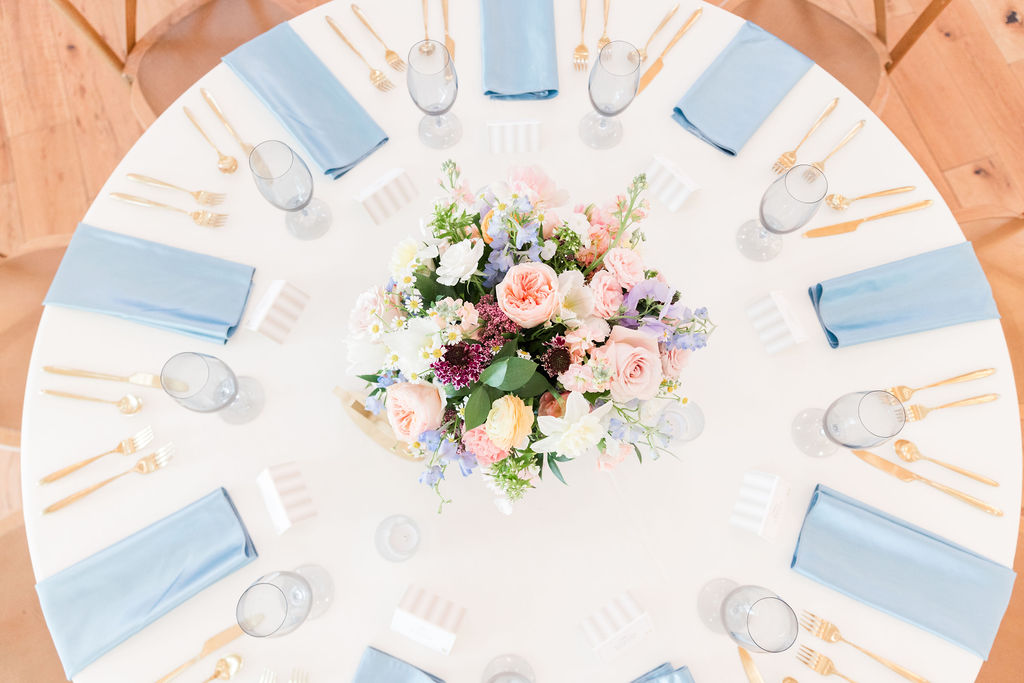 A luxury table setting perfect for a spring wedding with pastel soothing colors in the elegant florals and place settings.