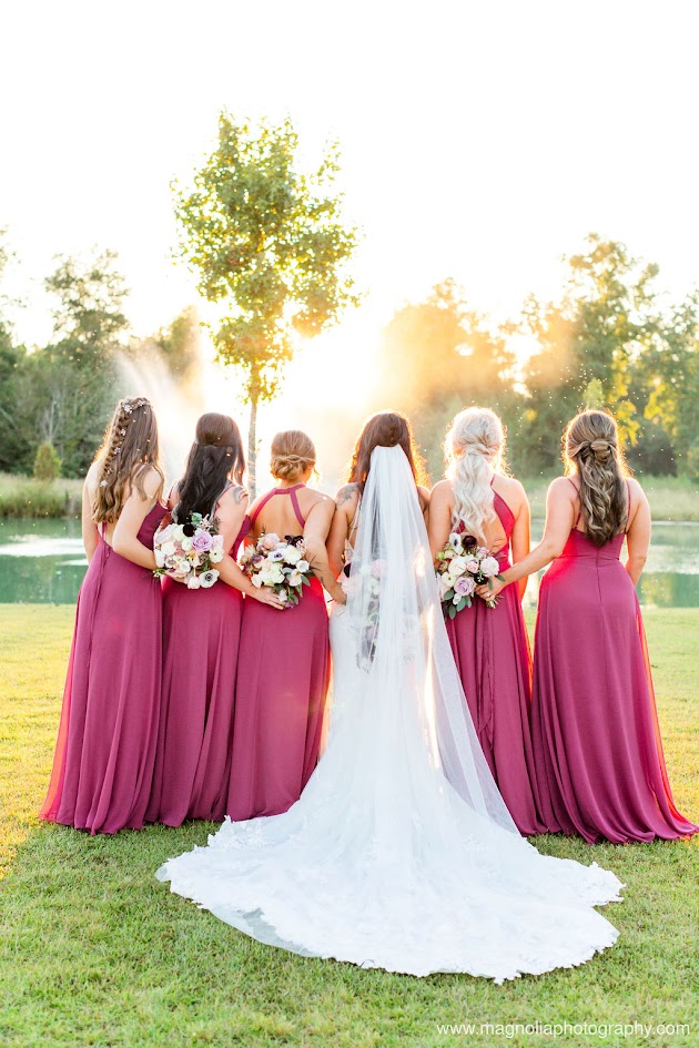a bride and her bridal party facing the sunset holding their elegant white, purple and pink lush bouquets