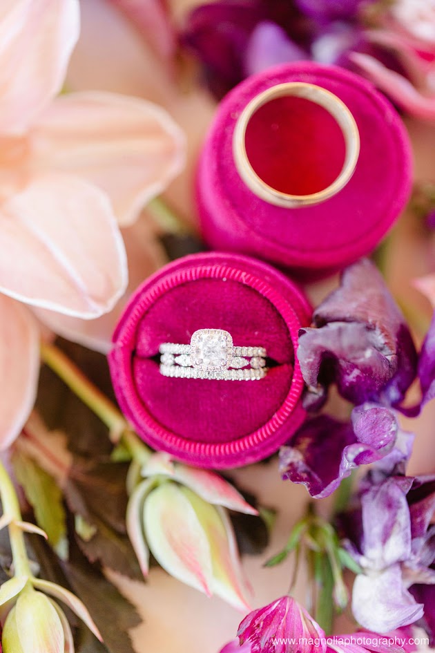 Elegant bridal details with diamond engagement ring in a fuschsia velvet box sitting on beautiful deep plum and blush florals.