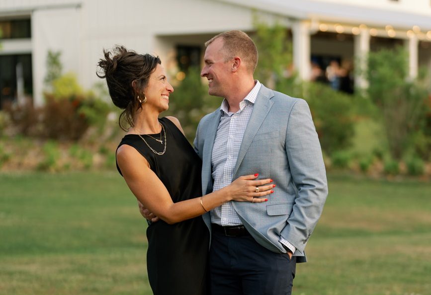 Couple dressed up outdoors, a woman in a black dress and a man in a light gray blazer, at White Oaks Farm near Myrtle Beach SC